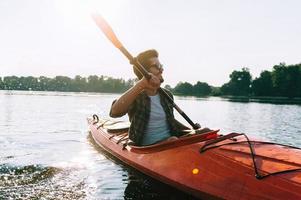 hombre en kayak. apuesto joven kayak en el lago y sonriendo foto