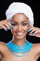 Bright emphasis. Beautiful African woman wearing white headscarf and smiling while looking at camera and standing against black background photo