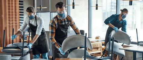 Young male waiters in protective workwear arranging furniture in restaurant photo