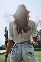 In her own style. Rear view of young woman keeping lavender in back pocket of her jeans while standing outdoors photo