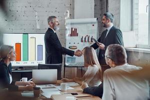 Modern businessmen shaking hands while working together with their team in the board room photo