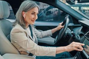 Mature beautiful woman in smart casual wear using global positioning system while driving car photo
