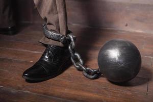 Shackles on his hand. Top view of businessman leg with shackles on it photo