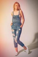 Beauty in denim style. Full length studio shot of beautiful young woman wearing jeans overall over the naked body and looking at camera photo