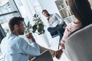 él sabe exactamente qué decir. joven pareja casada hablando mientras se sienta en la sesión de terapia con el psicólogo foto