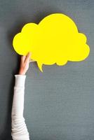 Cloud for your advertisement. Close-up of woman stretching out empty speech bubble against grey background photo