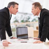 Business confrontation. Two mature men in formalwear conflicting while standing face to face photo