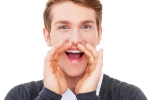 Sharing good news. Happy young man keeping arms raised and looking at camera while standing isolated on white photo