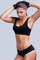 Loving my body. Beautiful young sporty woman with perfect body posing against grey background photo