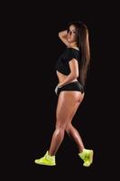 Sports training. Full length of beautiful young woman training on black background photo