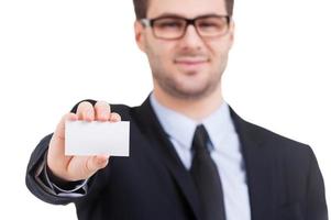 Copy space on his business card. Cheerful young man in formalwear showing his business card and smiling while standing isolated on white photo