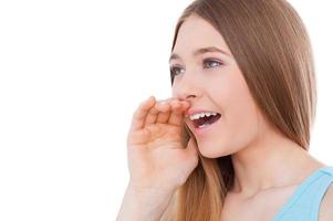 Sharing good news. Side view of cheerful teenage girl shouting and holding hand near mouth while standing isolated on white photo