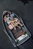 Two hearts full of love. Top view of beautiful young couple taking selfie using smart phone while lying in the boat photo