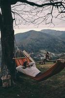 Time to rest. Handsome young man lying in hammock while camping with his girlfriend photo