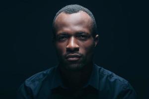 Confident and handsome. Portrait of handsome young African man looking at camera while being in front of black background photo