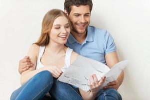 hermosa pareja amorosa. hermosa joven pareja amorosa sentada en el suelo y leyendo un folleto juntos foto