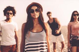 So young and so free. Four beautiful young people looking at camera while standing on the beach together photo