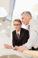 Discussing business. Two confident business men discussing something while holding papers in their hands photo