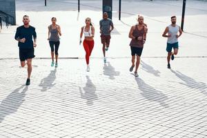 Full length top view of people in sports clothing jogging while exercising on the sidewalk outdoors photo