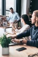 Taking important decision. Group of young business people using blackboard with adhesive notes while working in the office photo