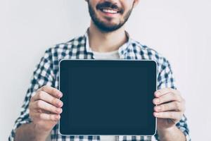 Copy space on his tablet. Close-up of young man showing his digital tablet and smiling photo