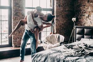 Feeling playful. Young passionate couple having fun together and looking happy while handsome young man carrying his girlfriend on shoulders photo