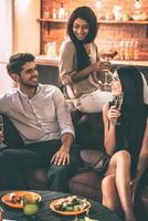 Friendly talk. Cheerful young people enjoying food and drinks while spending nice time in cofortable chairs at home together photo