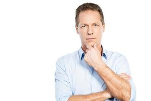 Confident mature man. Confident mature man looking at camera and holding hand on chin while standing against white background photo