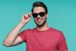 retrato de un joven apuesto con gafas de sol mirando a la cámara y sonriendo foto