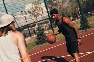 Playing fair. Two young men in sports clothing playing basketball while spending time outdoors photo