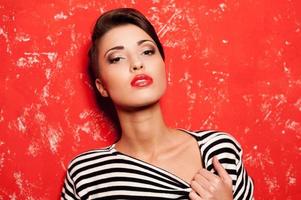 Beauty in style. Fashionable young short hair woman in striped clothing posing against red background photo