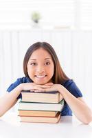 hermoso ratón de biblioteca. bella joven asiática leyendo un libro mientras se sienta en la mesa foto