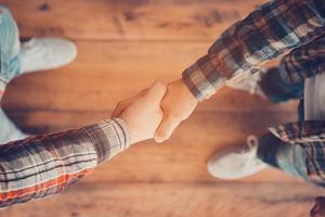 Men shaking hands. Top view of two men shaking hands while standing on the wooden floor photo