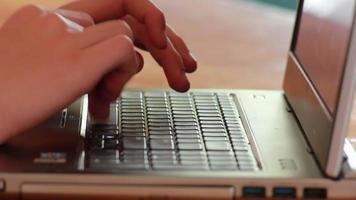 manos de un joven escribiendo en el teclado de un cuaderno de color oscuro video