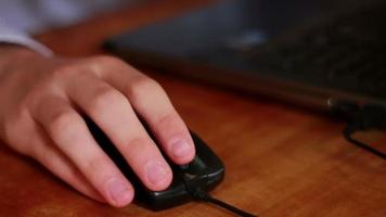 Hand of a man working at computer clicking on mouse on dark desktop video