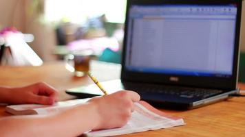 Male hands writing on a notebook near a computer video