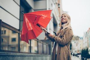 No more rain Low angle view of attractive young woman carrying umbrella and looking up with smile while standing on the street photo