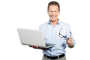 How may I help you Happy mature man in shirt holding laptop and smiling while standing against white background photo