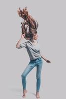 Keep moving Full length studio shot of attractive young woman with tousled hair posing against grey background photo