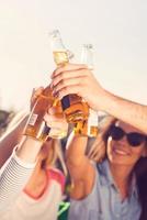 Beer time Close-up of young cheerful people cheering with beer while sitting outdoors together photo