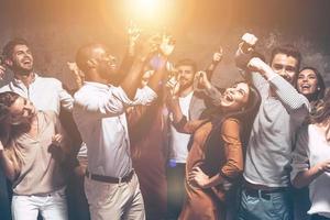 son imparables. grupo de hermosos jóvenes bailando juntos y luciendo felices foto