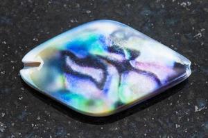 iridescent bead from haliotis shell on dark photo