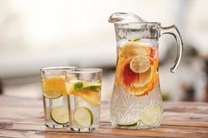 Drink healthy Close-up of jar and two glasses with lemonade on the wooden table photo