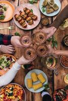 Cheers to friends Top view of four people cheering with wine while sitting at the rustic dining table photo