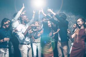 disfrutando de una fiesta genial juntos. grupo de hermosos jóvenes bailando juntos y luciendo felices foto