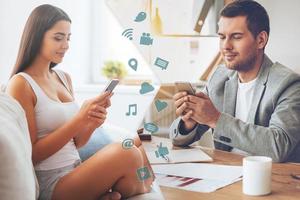 te extraño montaje de dos imágenes con hombres y mujeres mirando sus teléfonos inteligentes y sonriendo mientras están sentados en diferentes lugares foto