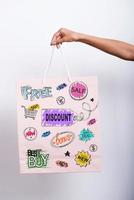 Shopping advantages. Close-up of female hand holding shopping bag with colorful sketches on it photo