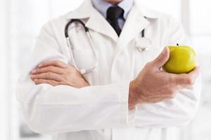 Choose a healthy lifestyle Cropped image of doctor in white uniform holding an apple photo