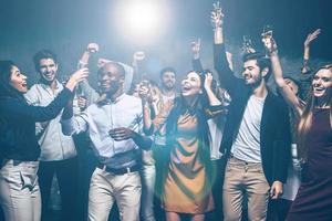 fiesta con amigos. grupo de hermosos jóvenes bailando juntos y luciendo felices foto