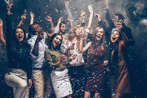 Party fun. Group of beautiful young people throwing colorful confetti and looking happy photo